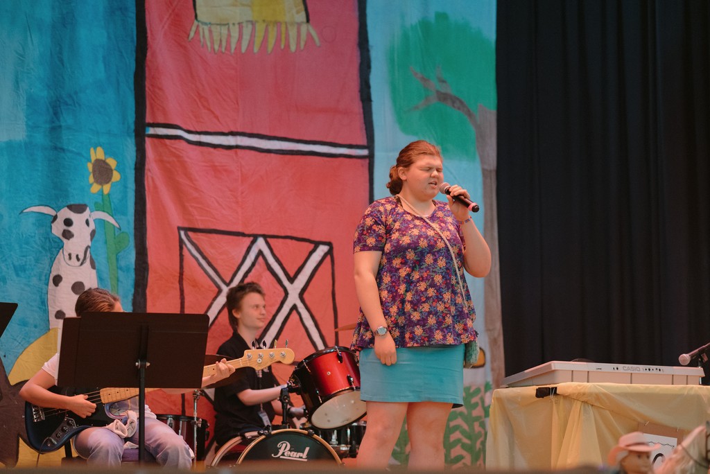 Students are performing on stage with country decor in the background.