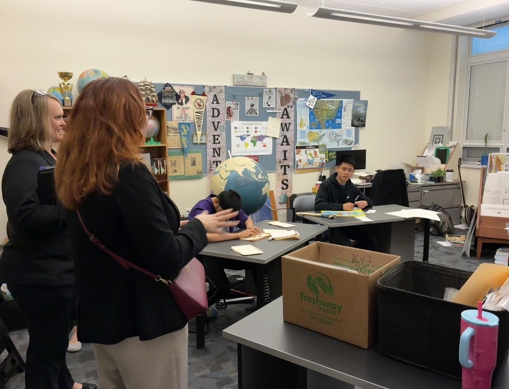 Dr. Maxlow and Ms. Conner talking to two male students in a classroom as they work