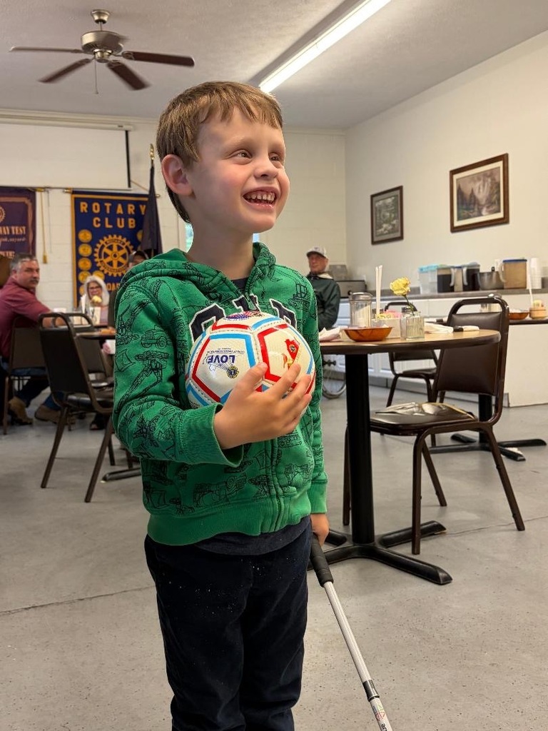Sammy holding his ball and white cane and smiling for the camera