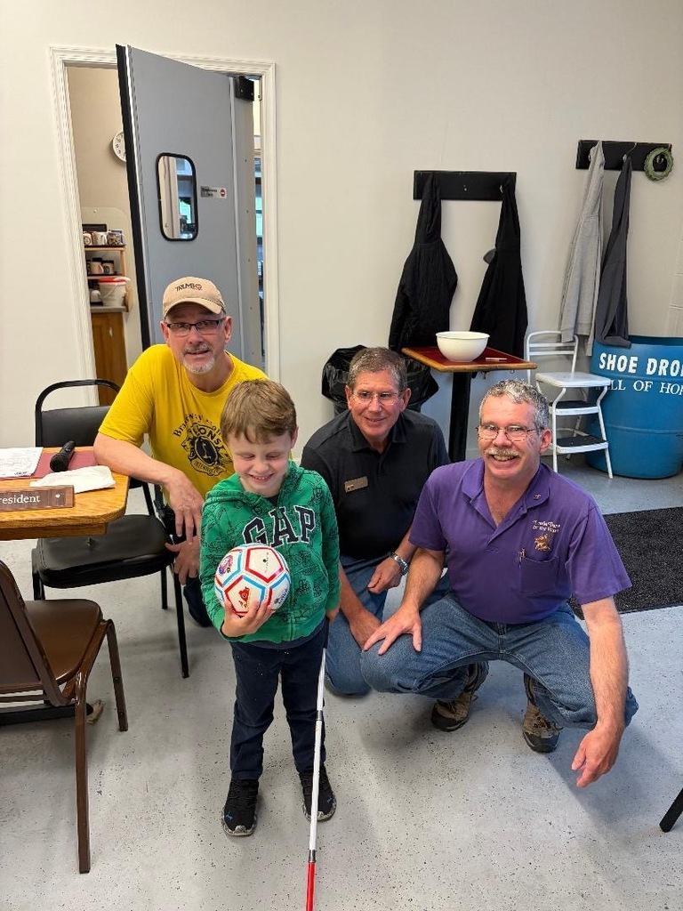 Sammy with Chuck Schwab and two other Lions. Sammy is holding his white cane and his ball. 