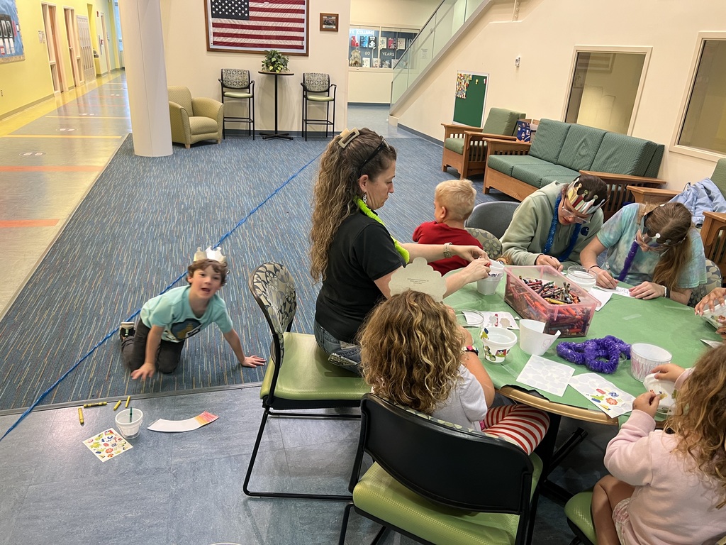 group working on a craft around a table, one child doing his craft on the floor