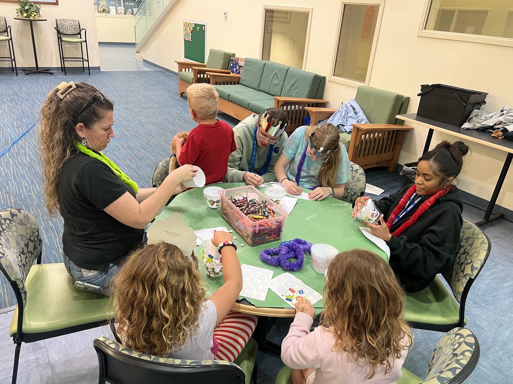 young children, teenagers, and two staff around a table working on crafts