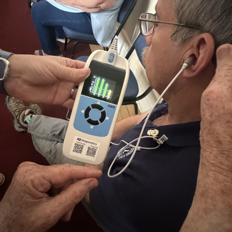 OAE machine screen showing testing results while the testing probe is in a man’s ear