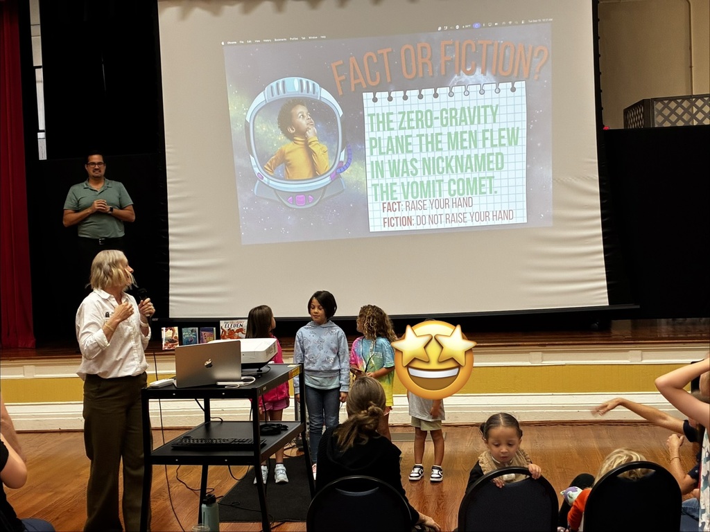4 young students standing in front of the projector screen while playing a "fact or fiction" trivia game from Kerry