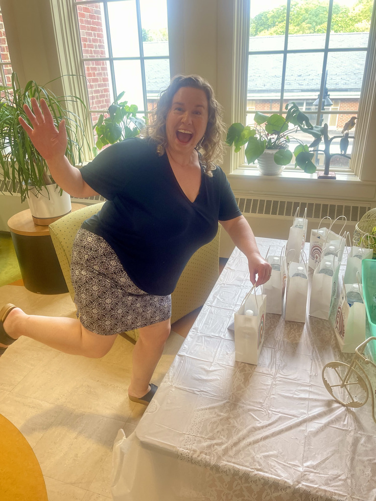 woman with an excited face picking up a goodie bag and posing for the camera