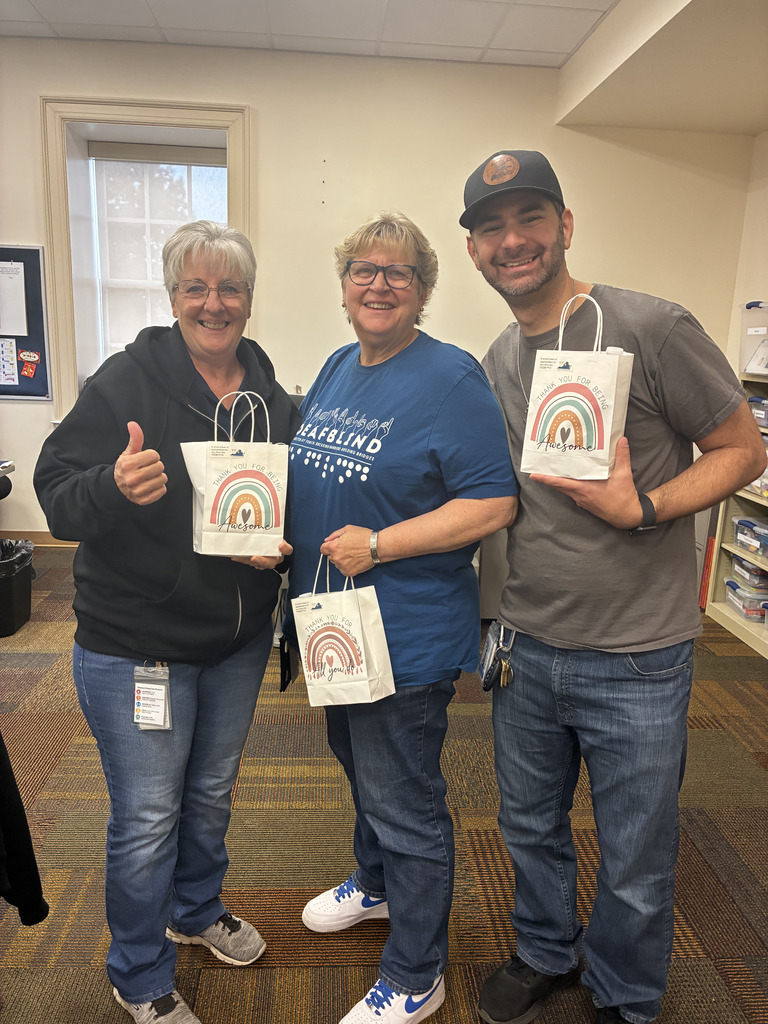 three staff standing together with their goodie bags, smiling