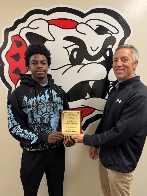 Quintin Brunson, Athlete of the month receives his award from an Edward Jones employee