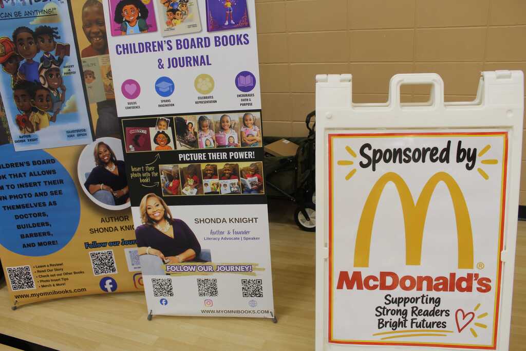 A McDonald's sign sits next to two promotional stands with colorful illustrations of children and adults.