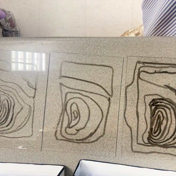 Three abstract drawings on a gray background. Shapes include a spiral, a half-circle, and a layered curve.