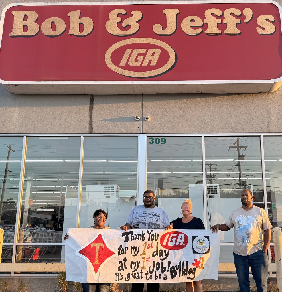 Three people pose in front of Bob & Jeff's IGA, holding a banner that reads "Thank You for my 1st day at my Job!"