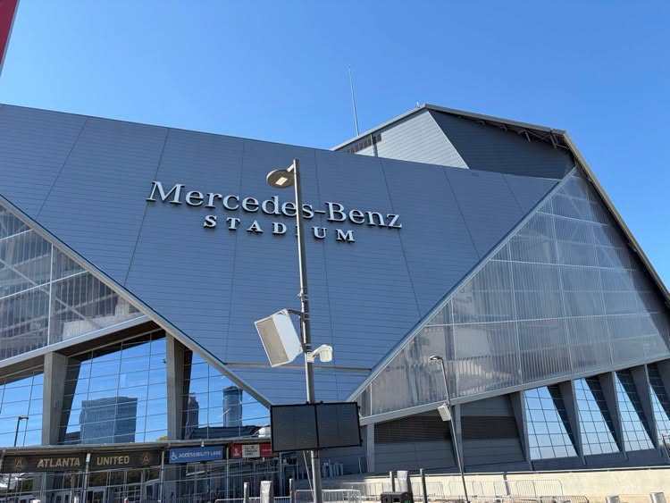 Modern building with "Mercedes-Benz Stadium" written on the front. Clear sky visible.
