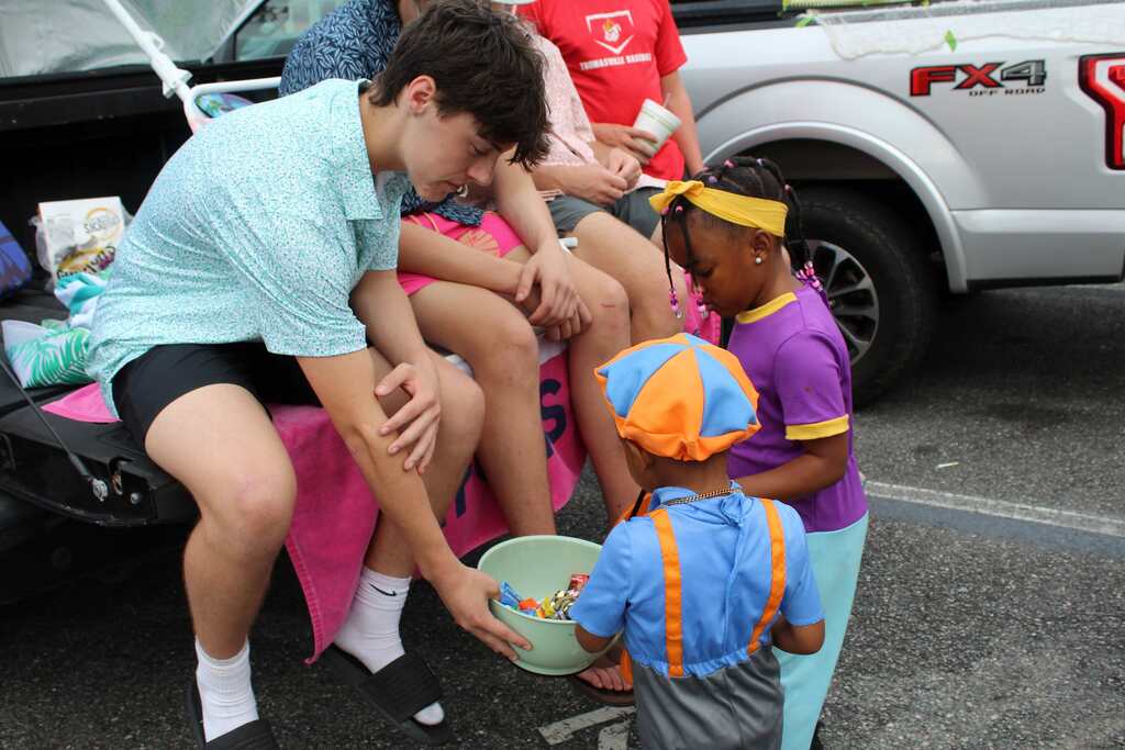 A person with a bowl in their hands stands and looks down at a seated child.