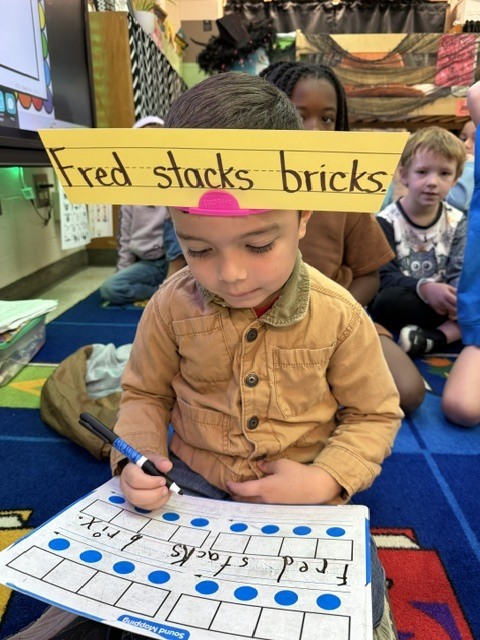 Students wearing headbands to practice sentence writing.