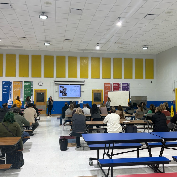 picture of the cafeteria with parents listening to a presenter