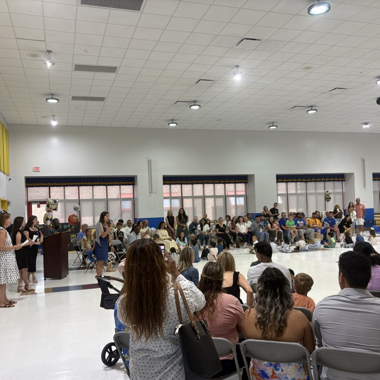 room filled with parents and students. principal speaking on microphone