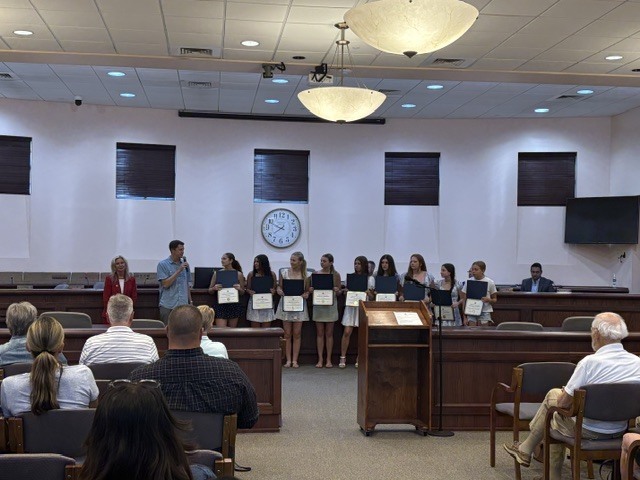 Mayor, coach and softball team players standing in the Tinton Falls Court Room during a Council Meeting