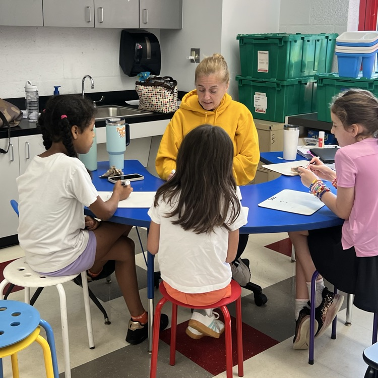 teacher sitting with students reading 