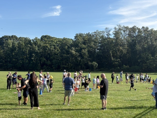 A field with children, parents and teachers participating in field day