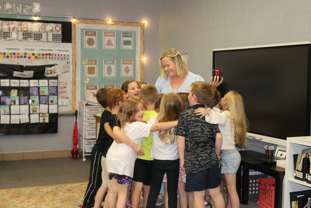 Students hug their teacher after she received the Golden Apple Award.