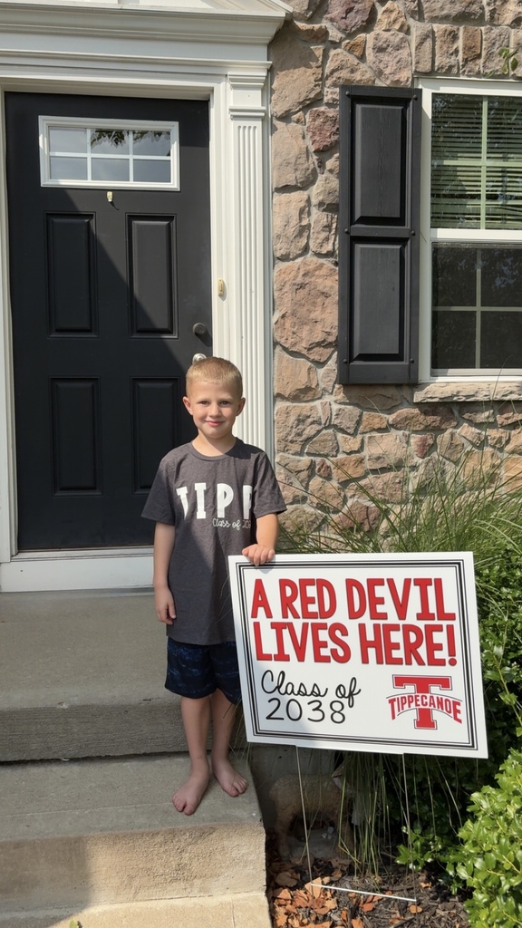 Kindergarten student standing with the yard signing saying A Red Devil Lives Here!