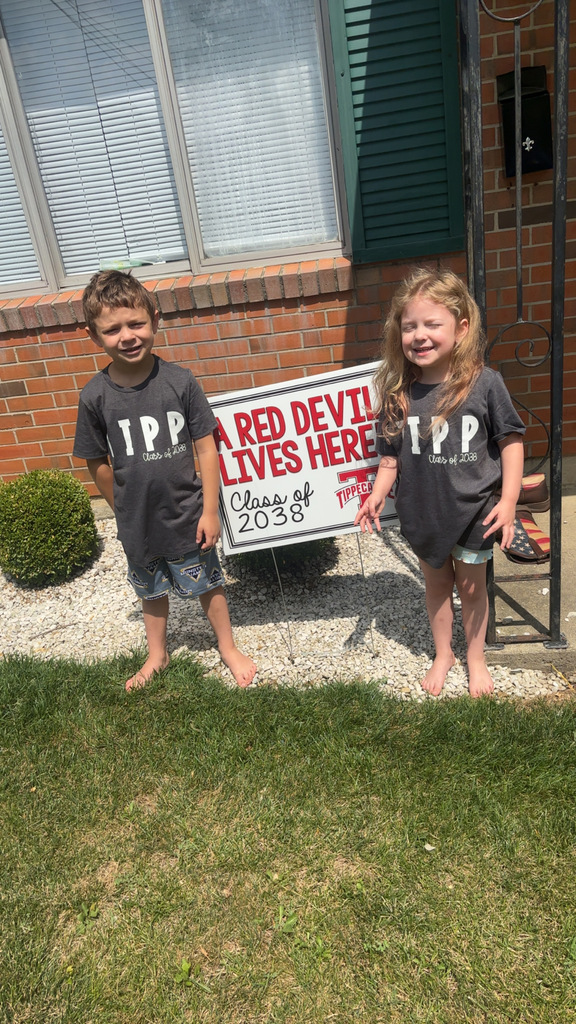 Kindergarten student standing with the yard signing saying A Red Devil Lives Here!