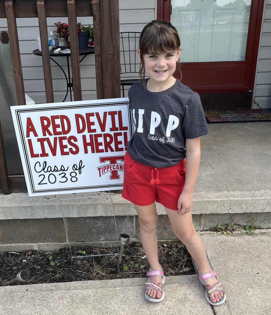 Kindergarten student standing with the yard signing saying A Red Devil Lives Here!