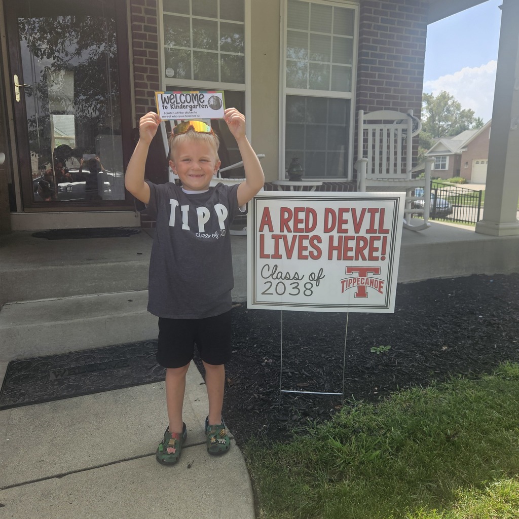 Kindergarten student standing with the yard signing saying A Red Devil Lives Here!