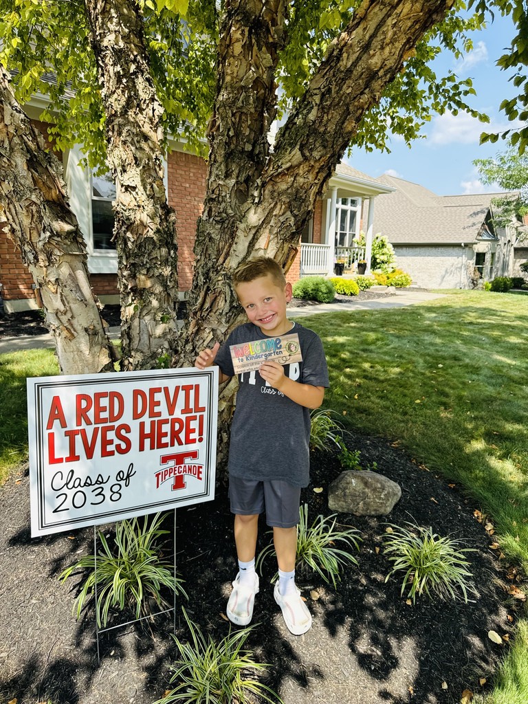 Kindergarten student standing with the yard signing saying A Red Devil Lives Here!