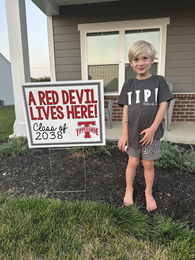 Kindergarten student standing with the yard signing saying A Red Devil Lives Here!