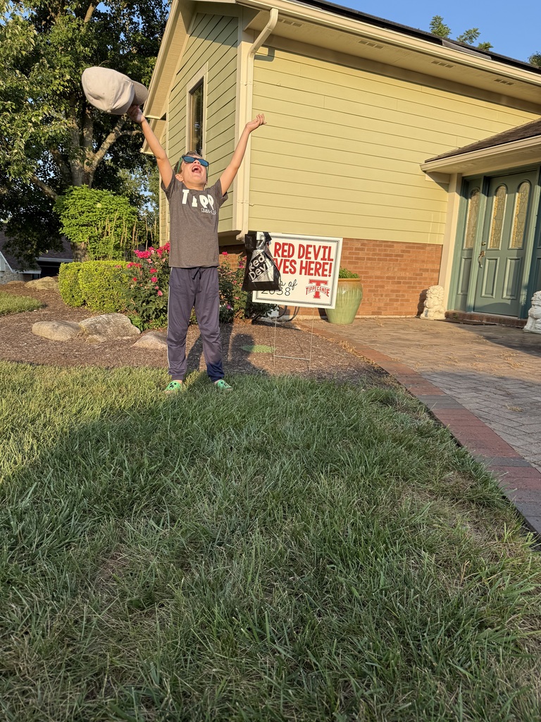 Kindergarten student standing with the yard signing saying A Red Devil Lives Here!