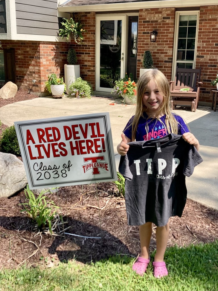 Kindergarten student standing with the yard sign saying A Red Devil Lives Here!