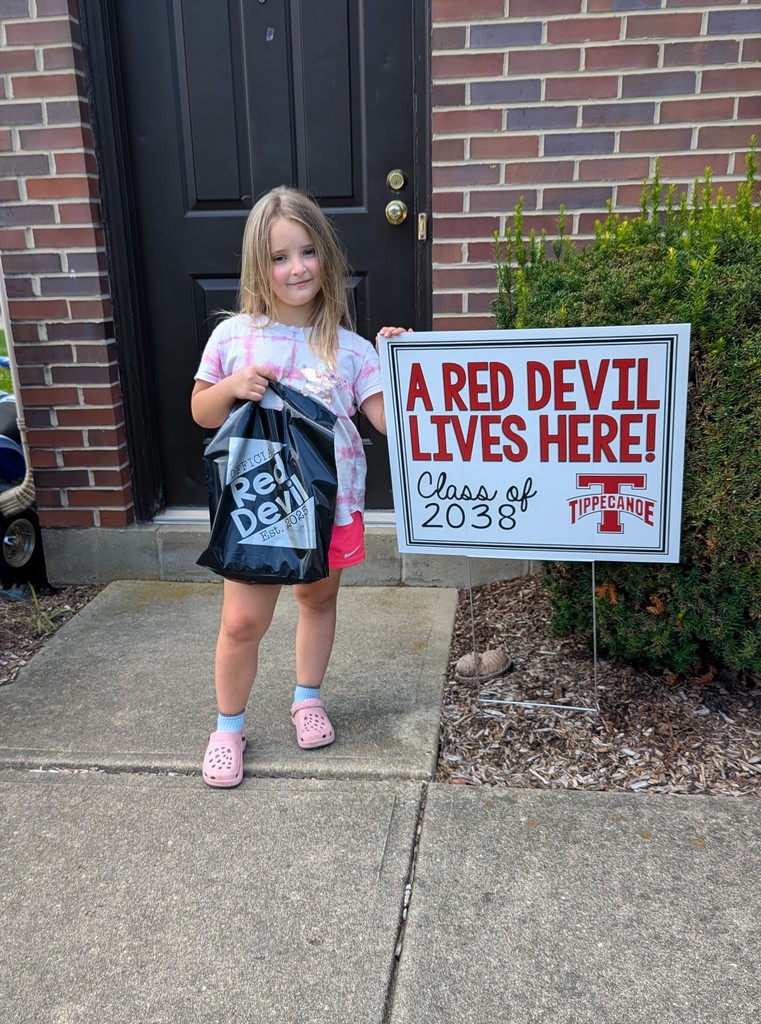 Kindergarten student standing with the yard sign saying A Red Devil Lives Here!