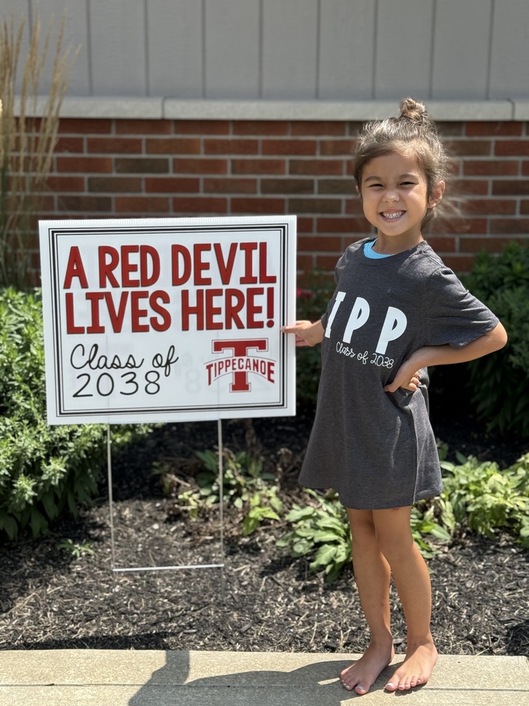 Kindergarten student standing with the yard sign saying A Red Devil Lives Here!