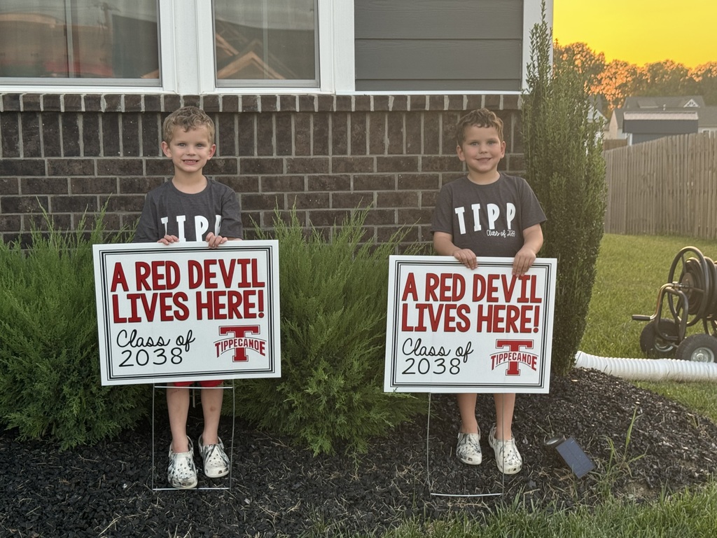 Kindergarten students standing with the yard signs saying A Red Devil Lives Here!