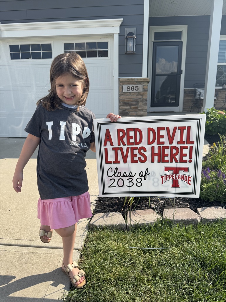 Kindergarten student standing with the yard sign saying A Red Devil Lives Here!
