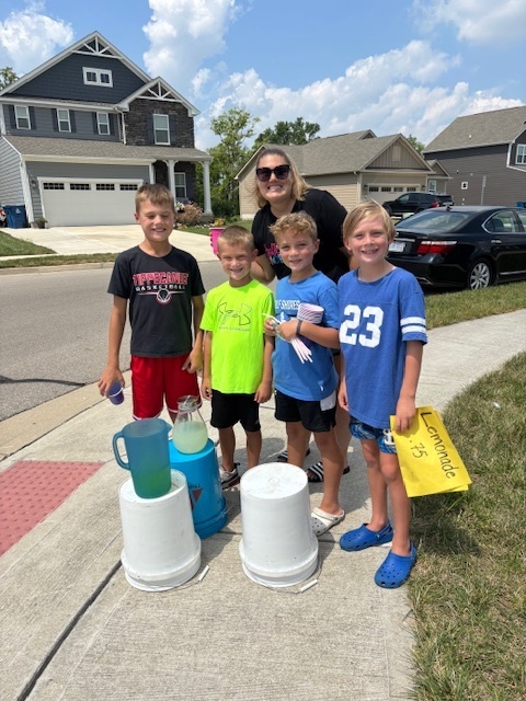 A kindergarten teacher with students at their lemonade stand.  