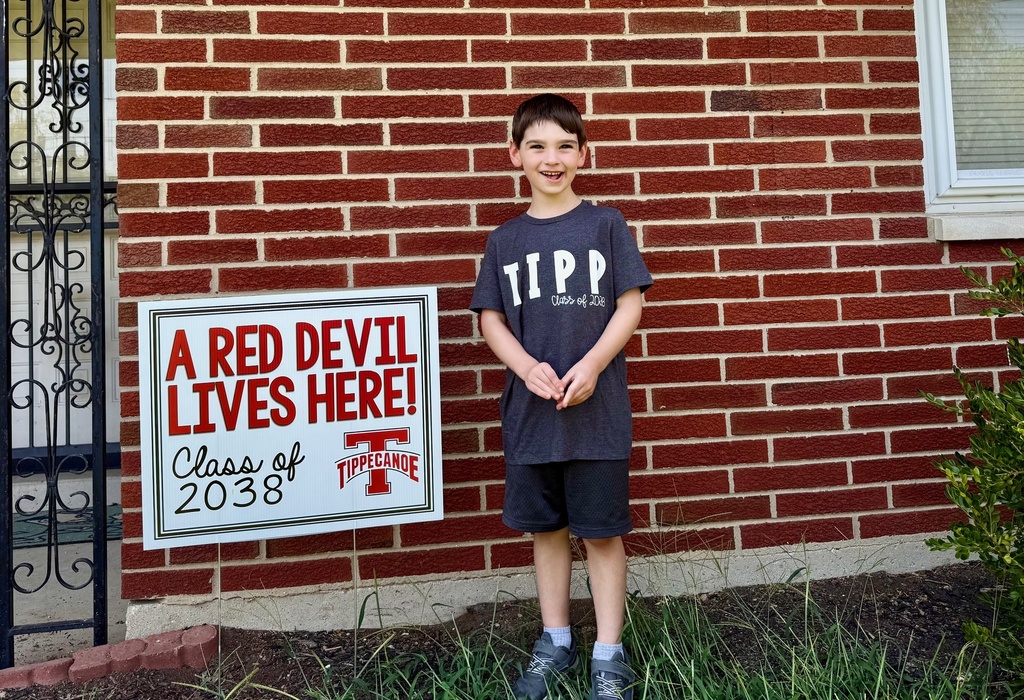 Kindergarten student standing with the yard signing saying A Red Devil Lives Here!