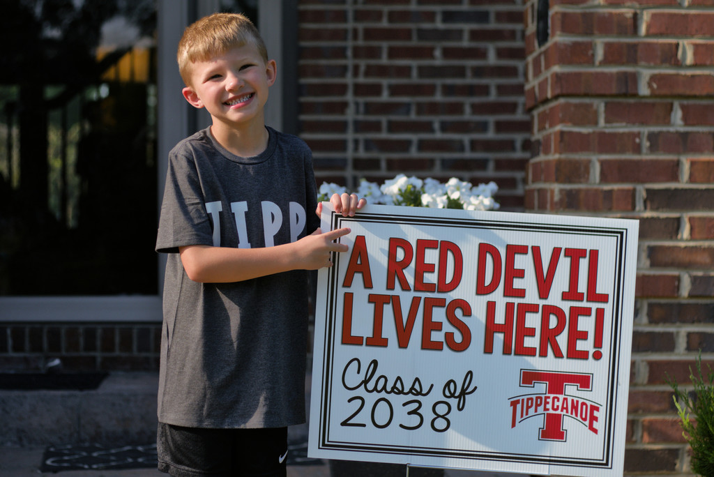 Kindergarten student standing with the yard signing saying A Red Devil Lives Here!
