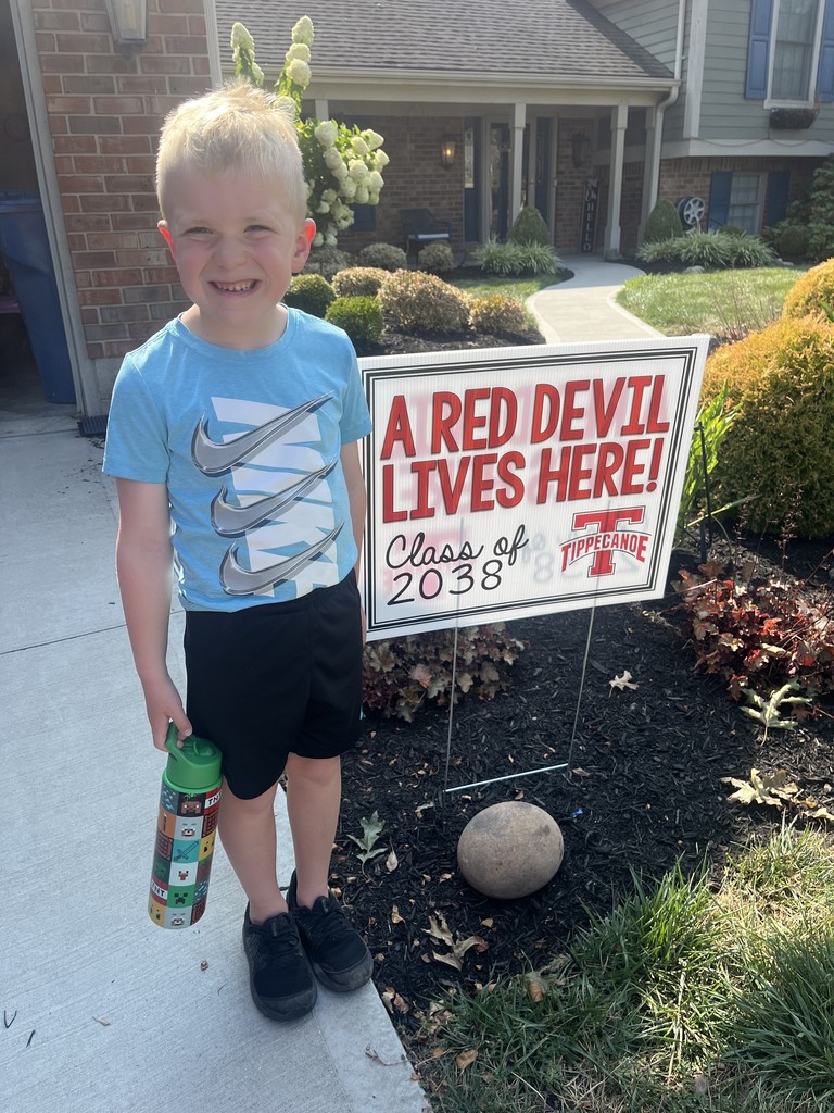 Kindergarten student standing with the yard signing saying A Red Devil Lives Here!