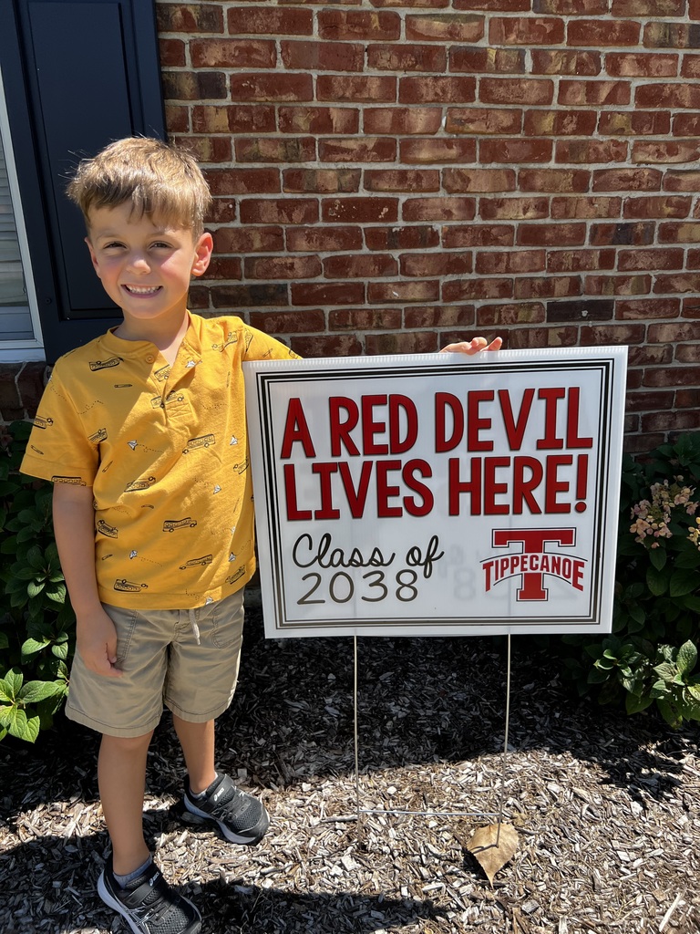Kindergarten student standing with the yard signing saying A Red Devil Lives Here!