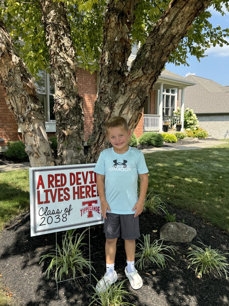 Kindergarten student standing with the yard signing saying A Red Devil Lives Here!