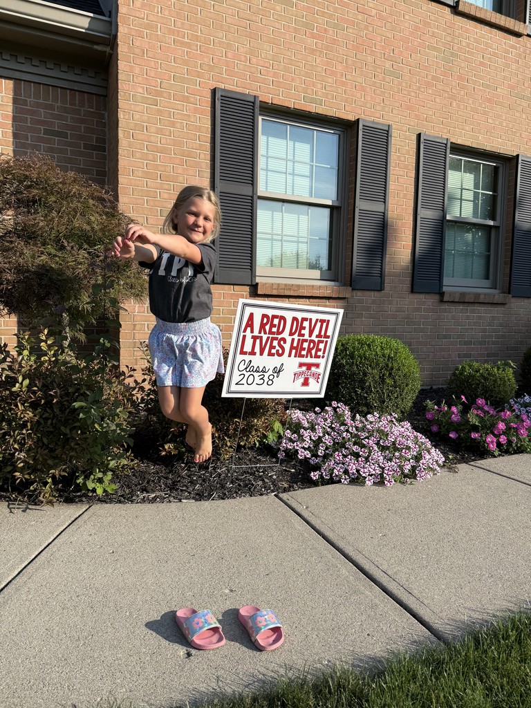 Kindergarten student standing with the yard signing saying A Red Devil Lives Here!
