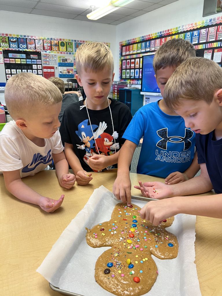 Students are decorating a large cookie.