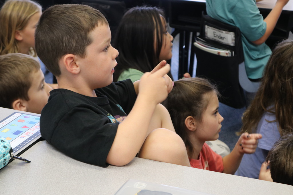 First graders make hand motions for a book.  