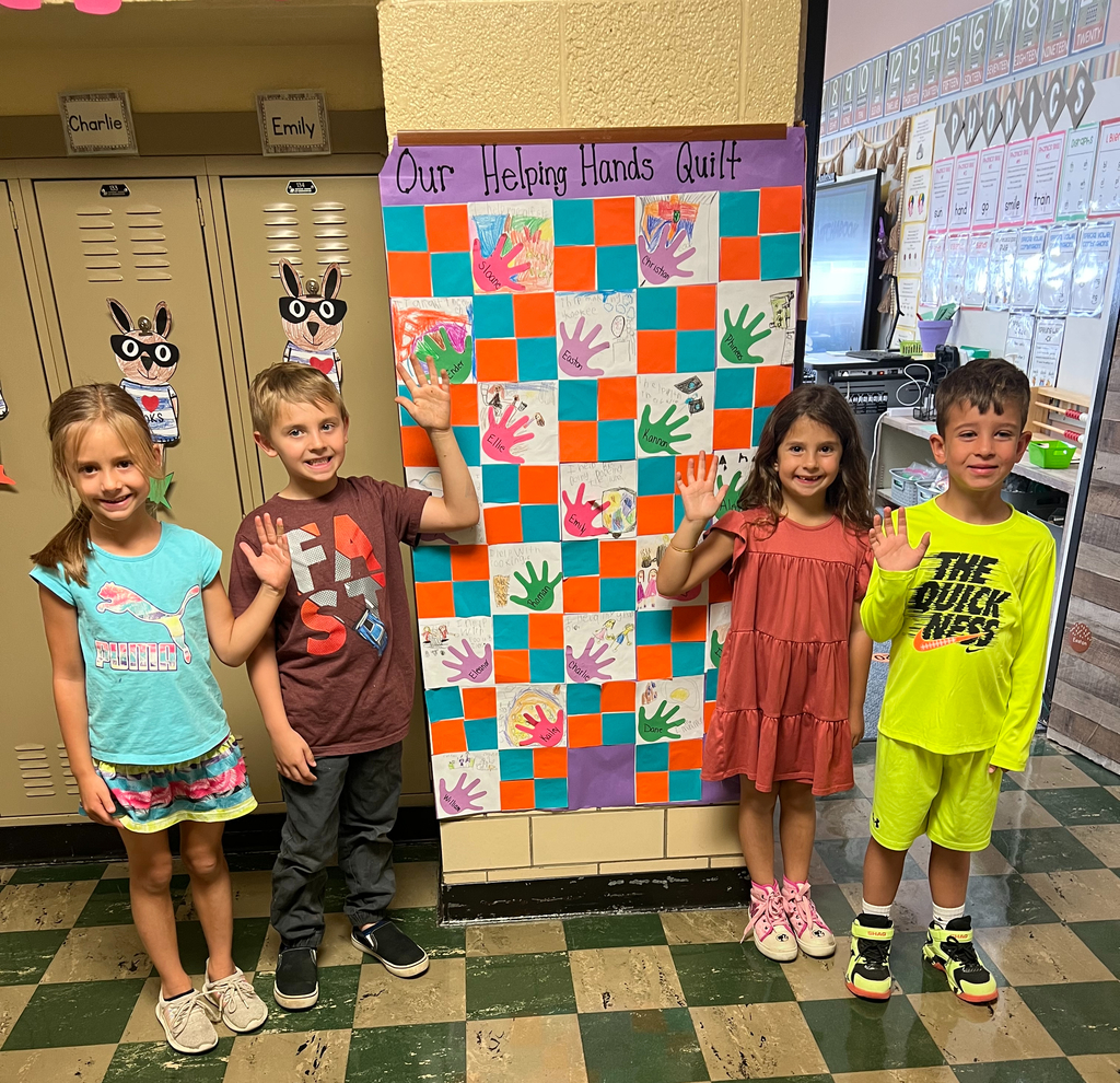 Helping Hands Quilt with four students posing with the project.