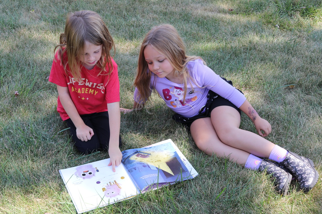 Students reading on the lawn during a visit from Tipp City Public Library.