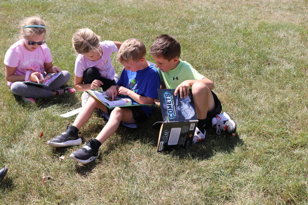 Students reading on the lawn during a visit from Tipp City Public Library.