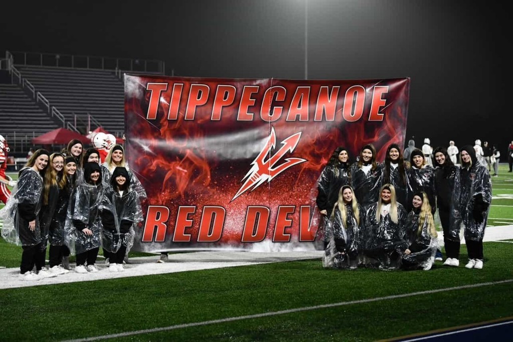 THS cheerleaders pose with the run-through banner donated by Expressions Studios.