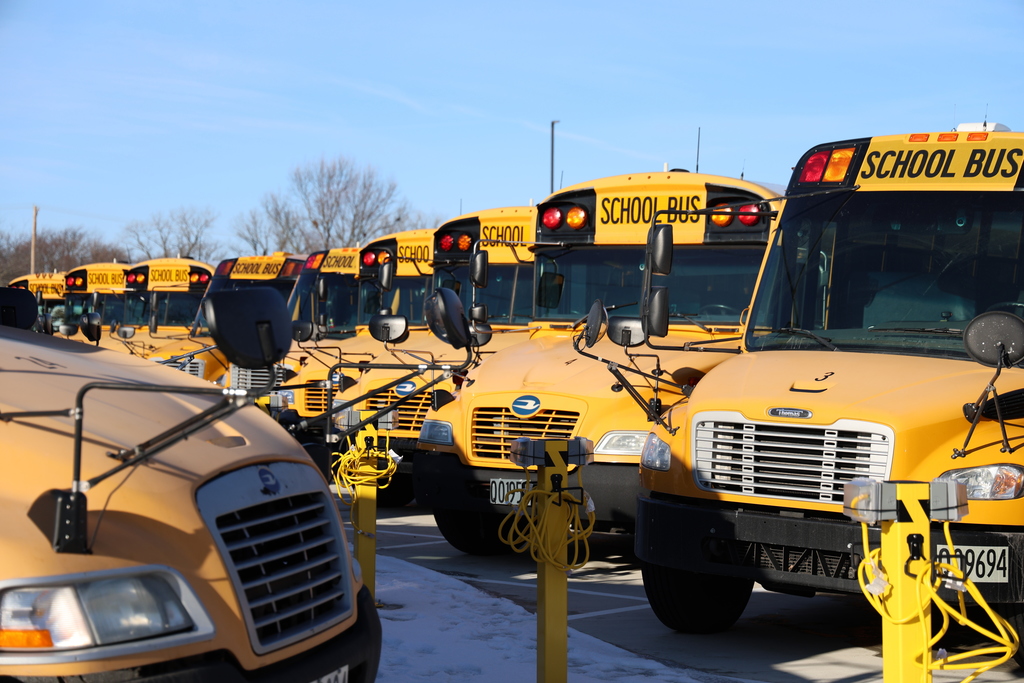 A row of school buses in the new parking lot.  