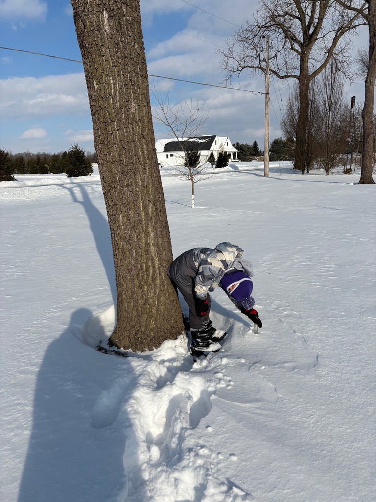 A student is measuring snow during the Online Learning Day.